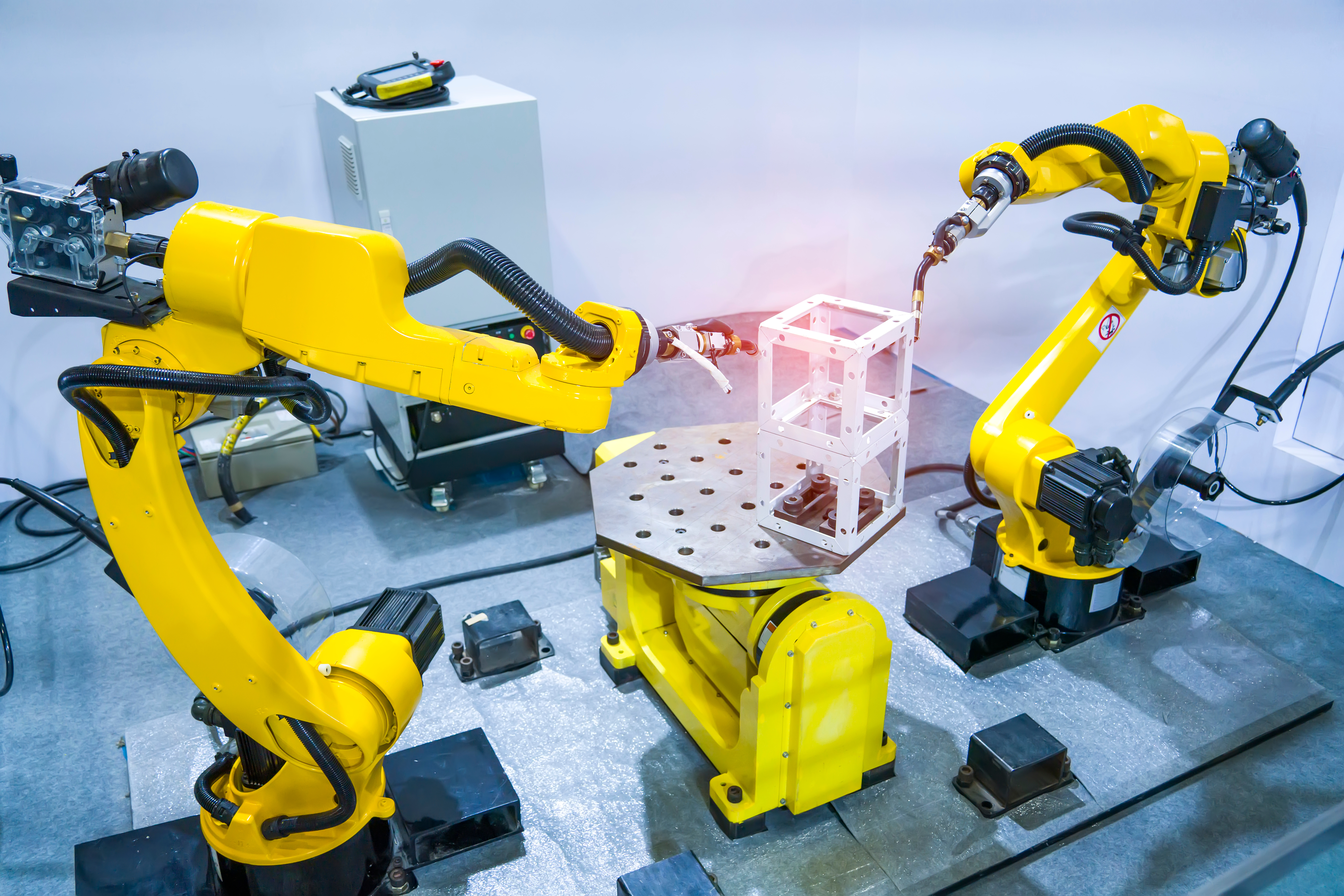 Industrial robotic welders arms weld the car part on factory on manufacture of the Assembly line Industrial robotic welders arms weld the car part on factory on manufacture of the Assembly line